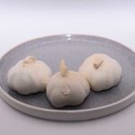 3 knoflook bollen op een blauw bordje, klaar om in te vriezen.