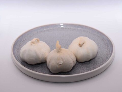3 knoflook bollen op een blauw bordje, klaar om in te vriezen.