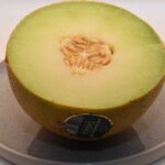 Een doormidden gesneden galia meloen ligt op een bordje.